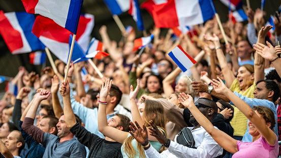 Photo d'une tribune de supporters qui tiennent des drapeaux français.